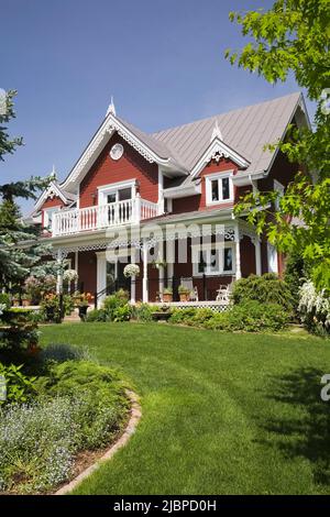 Borgogna con finiture bianche Casa vittoriana stile cottage delimitato da Spiraea x vanhouttei 'Van Houtte' - Spirea, Syringa vulgaris - Lilac albero in primavera. Foto Stock