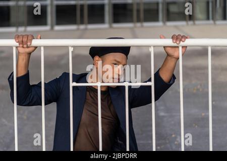 Latino gay maschio con trucco indossando cappello di moda in posa per strada Foto Stock