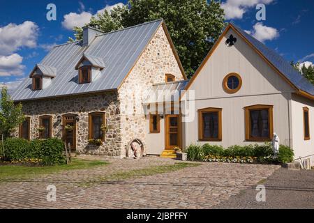 Replica del vecchio 1700s francese regime cottage stile fieldstone casa con tetto in lamiera grigia e l'estensione in primavera. Foto Stock