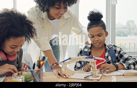 Classe con diversi studenti di studenti felicemente afroamericani e insegnanti che svolgono attività insieme. L'insegnante sta insegnando, guidando e talki Foto Stock