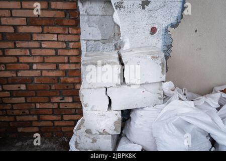 Detriti di costruzione sullo sfondo del muro di una casa privata. Smontaggio isolamento parete. Blocco di calcestruzzo fessurato Foto Stock