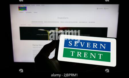 Persona che tiene lo smartphone con il logo della società britannica di acqua Severn Trent plc sullo schermo di fronte al sito web. Mettere a fuoco sul display del telefono. Foto Stock