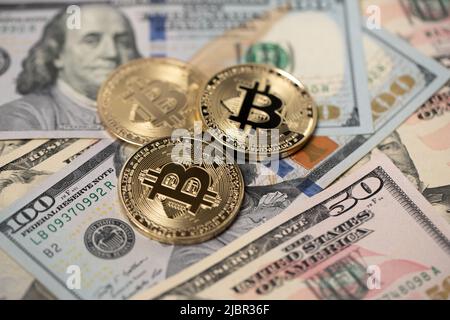 Monete in oro bitcoin su di cento banconote da dollari. Cambio BTC a USD. Valuta degli Stati Uniti d'America. Foto Stock