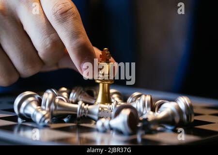 Closeup shot delle mani di un irriconoscibile imprenditore tenendo due re e facendoli combattere sulla scacchiera Foto Stock