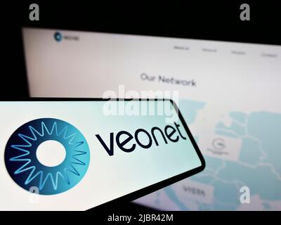 Smartphone con logo della rete clinica oftalmologica Veonet GmbH sullo schermo di fronte al sito web aziendale. Messa a fuoco al centro-sinistra del display del telefono. Foto Stock