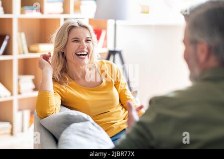 Buone sposi di mezza età che chiacchierano e Laughing mentre si rilassano insieme a casa Foto Stock