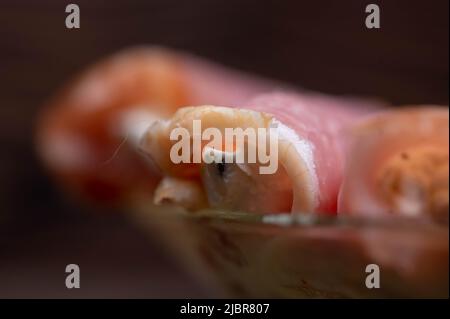 Un rotolo di carne secca e formaggio morbido su un piatto di vetro sul tavolo. Tavolo festivo. Foto Stock