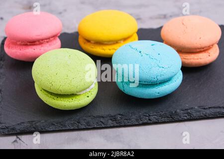 Macaron colorati e luminosi biscotti sfondo grigio. Foto Stock