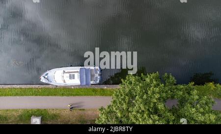 Foto dall'alto in basso del drone aereo di un piccolo yacht di lusso ancorato al molo sul fiume. Foto di alta qualità Foto Stock