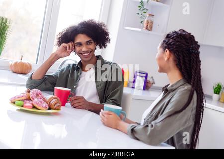 Foto di bella coppia hanno conversazione in cucina sala bere cioccolata calda Godetevi yummy deliziosi biscotti ciambelle Foto Stock