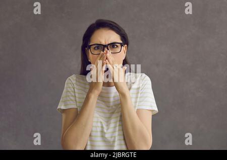 Ritratto di giovane donna che ricopre la bocca con le mani spaventato o disgustato da qualcosa Foto Stock
