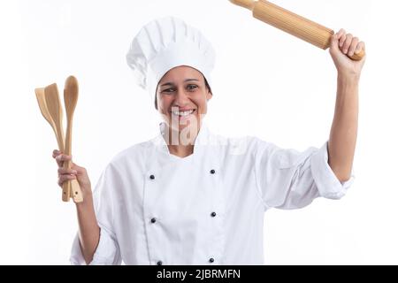 Felice giovane ispanica ragazza in uniforme di cuoco tenendo gli utensili isolati su uno sfondo bianco . Foto Stock