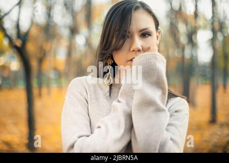 Ritratto di una bella donna asiatica che cammina all'aperto. Bella donna in un maglione. Ritratto di moda di bella donna elegante all'aperto Foto Stock