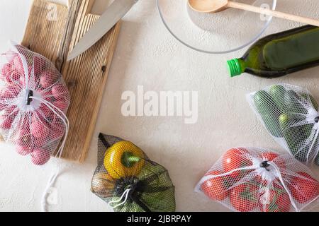 Prodotti per insalata vegetale in reti ecologiche su un tavolo leggero, prodotti sani e imballaggi senza rifiuti. Foto Stock