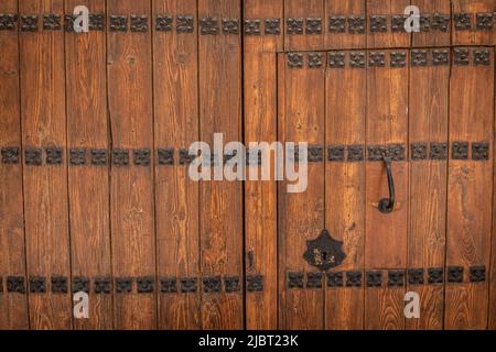 Doppia porta in legno massello verniciato e invecchiato con decorazioni in metallo antico, batticalcagno e serratura in nero Foto Stock