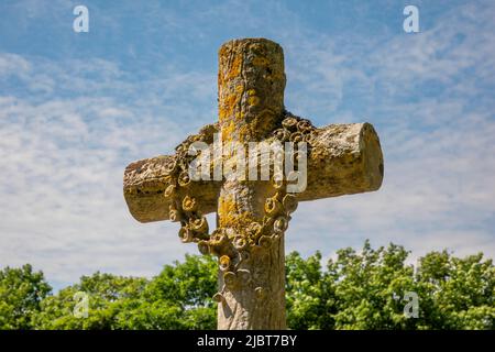 Croce Headstone con ghirlanda di fiori scolpiti contro un cielo azzurro, All Saints Church, Saxstead, Suffolk Foto Stock