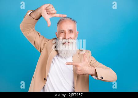 Ritratto di bell'uomo allegro ed elegante, dai capelli grigi, che mostra la cornice di ripresa isolata su sfondo di colore blu brillante Foto Stock