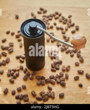 Macinacaffè manuale per macinare chicchi di caffè con chicchi di caffè e caffè macinato su sfondo di legno Foto Stock