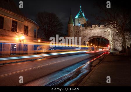 Porta St-Louis, arco nelle fortificazioni della città di Quebec di notte, mentre auto e autobus sono di passaggio, QC, Canada Foto Stock