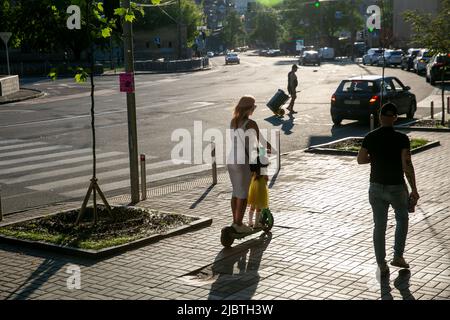 Una giovane donna con figlia guida su uno scooter elettrico nel centro di Kiev. Foto Stock