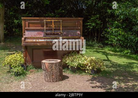 Un pianoforte dilapido in piedi da solo in un campo. Indesiderato, solitudine, abbandono o vacanza, cambiamento di scenario concetto. Foto Stock