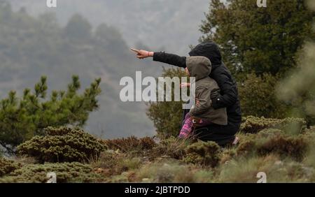 Fuoco selettivo sparato di donna e bambino che tiene le mani mostrando montagne insieme. Foto Stock