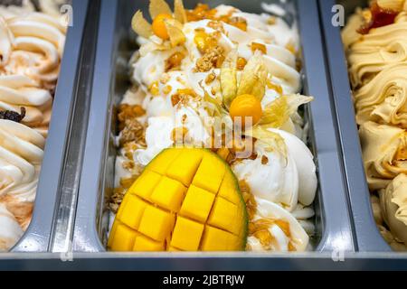 Gelato al mango con physalis. Vari gelati in vassoi nella gelateria vista dall'alto. Foto Stock