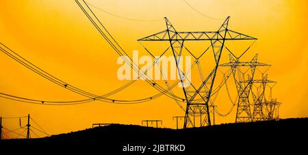 Linee elettriche che trasportano l'elettricità attraverso le torri alle persone nelle prime ore del mattino Foto Stock