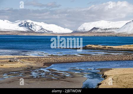 Strada asfaltata che attraversa il delta sabbioso di un piccolo fiume sulla costa settentrionale della penisola di Snaefelsnes, con montagne innevate sullo sfondo Foto Stock