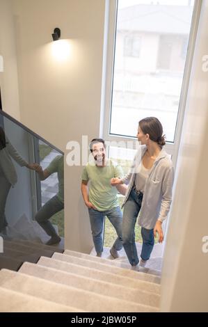Donna che sale scale girando intorno tenendo mano mans Foto Stock