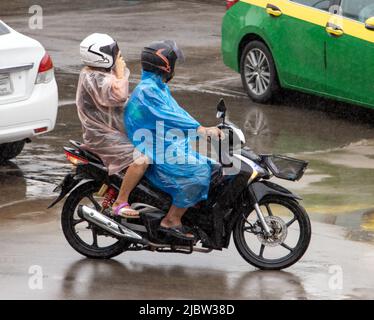 Una coppia con un impermeabile corre una moto sotto la pioggia Foto Stock