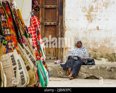 Città di pietra, Zanzibar, Tanzania - Gennaio 2021: Anziana donna africana pensiva seduta tra le mura di pietra della città africana Foto Stock