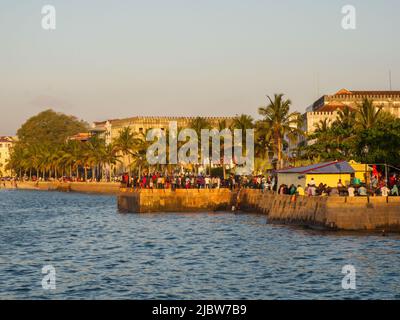 Città di pietra, Zanzibar, Tanzania - Jan 2021: Folla della gente sui giardini di Forodhani e bambini che saltano in acqua da un muro durante il tramonto. C Foto Stock