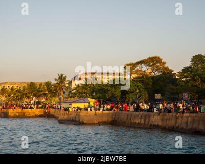 Città di pietra, Zanzibar, Tanzania - Jan 2021: Folla della gente sui giardini di Forodhani e bambini che saltano in acqua da un muro durante il tramonto. C Foto Stock