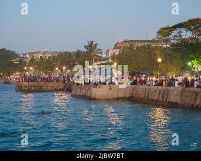 Città di pietra, Zanzibar, Tanzania - Jan 2021: Folla della gente sui giardini di Forodhani e bambini che saltano in acqua da un muro durante la serata ti Foto Stock