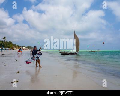 Zanzibar, Tanzania - Jan, 2021: Una tradizionale nave da sambuco a vela con un'enorme vela bianca sulle acque blu dell'oceano Indiano presso la spiaggia di surf in Foto Stock