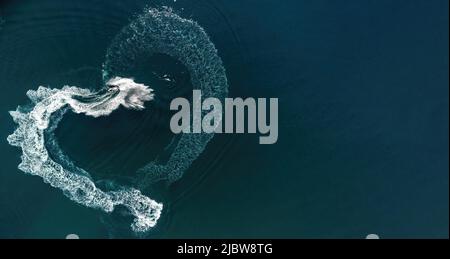 Vista aerea su una traccia a forma di cuore sul mare turchese da una moto d'acqua. San Valentino amore simbolo di forma del cuore, amore, sentimenti. Acqua splash amore Foto Stock