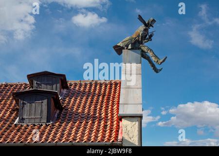 Il camino spazzare sul tetto di casa di Klaipeda in Lituania. Tetto di tegole rosse e cielo blu con nuvole bianche sullo sfondo. Foto Stock