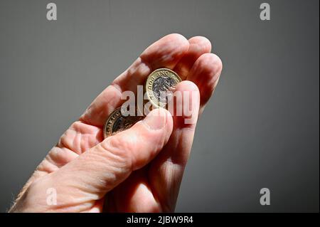 Primo piano delle monete in sterline britanniche tenute in mano a una persona anziana. Foto Stock