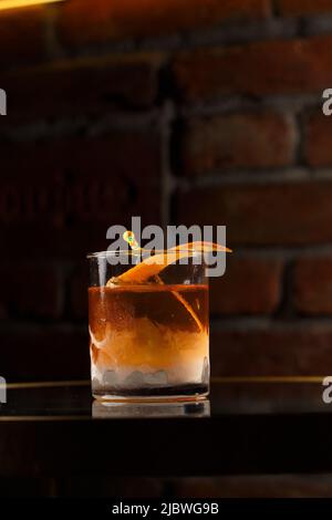 Cristallo di vetro con cocktail alcolici freddi e luminosi decorati con scorza d'arancio. Sfondo sfocato. Cocktail Negroni Foto Stock