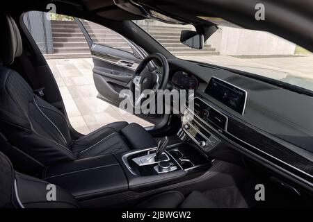 Interno BMW 740D con portiera del conducente aperta. L'interno è rifinito con legno e pelle nera. Katowice, Polonia - 13.06.2021 Foto Stock