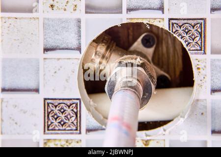 Tubo di collegamento intrecciato, tubo dell'acqua per l'alimentazione di acqua calda e fredda in casa rurale. Foto Stock