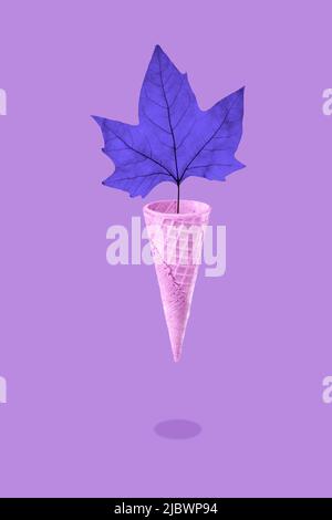 Brillante foglia di acero autunnale in un cono gelato a cialda, concetto di stagione. Foto Stock