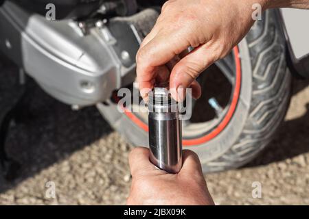 Cambio dell'olio, manutenzione e riparazione della motocicletta. Un meccanico dell'auto svita il tappo sull'ammortizzatore della forcella anteriore di una moto. Foto Stock