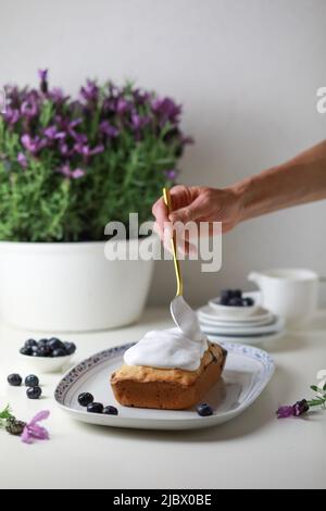 Donna che decora la torta bundt con vetri, vista ravvicinata della mano che decora la torta. Foto Stock