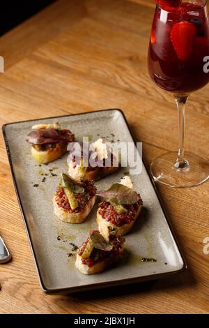 Quattro bruschette con tartare di manzo su un piatto, crostini con tartare di manzo, bruschetta di manzo, sandwich con manzo crudo gourmet Foto Stock