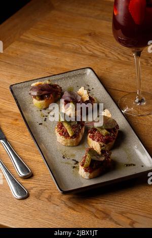 Quattro bruschette con tartare di manzo su un piatto, crostini con tartare di manzo, bruschetta di manzo, sandwich con manzo crudo gourmet Foto Stock