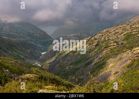 Skagway, Alaska, USA - 20 luglio 2011: Autostrada Klondike per il Canada. In fondo alla strada, la valle con laghetto sotto il paesaggio nuvoloso sopra la montagna verde Foto Stock