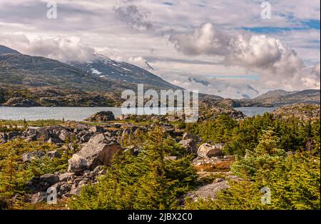 Skagway, Alaska, USA - 20 luglio 2011: Autostrada Klondike per il Canada. Nuvoloso paesaggio sulle Montagne Rocciose canadesi con le zone innevate e Summer Lake sul fondo A. Foto Stock