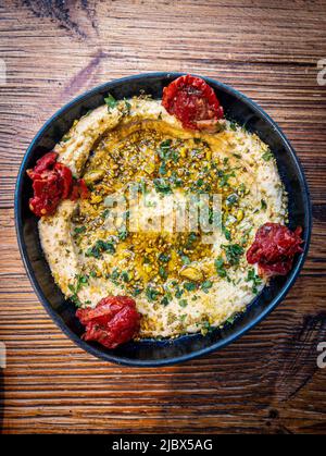 Hummus condito con semi di sesamo, olio d'oliva e coriandolo tritato. Foto Stock